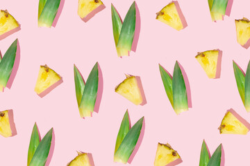 Creative pattern made with pineapple slices and green leaves on pastel pink background. Minimal flat lay. Creative idea with fruits. Spring or summer concept. © Adela