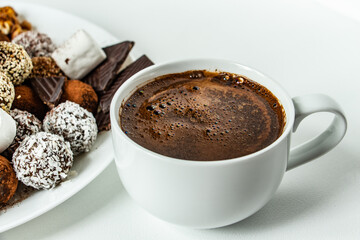 truffles with cocoa, coconut and sesame with chocolate and marshmallows and a cup of aromatic coffee, delicious dessert