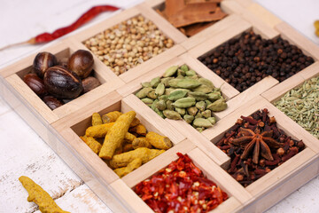 Indian spices for Indian cooking Masala hot spicy curry  whole spices turmeric, cardamom, black pepper in wooden spoon curry leaves paprika in Indian spice box Kerala India Sri Lanka.