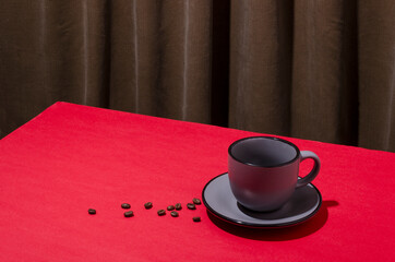 Grey cup, coffee beans on the red table against folds of curtains.Empty space