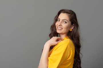 portrait of a young teenager with long wavy hair dressed in a yellow t-shirt, isolated on gray background