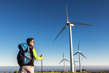 Male backpacker standing in field with windmills