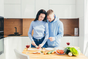 A young couple in love, a man and a woman, are cooking dinner together and having fun in a new apartment