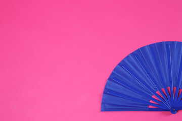 Blue hand fan on pink background, top view. Space for text
