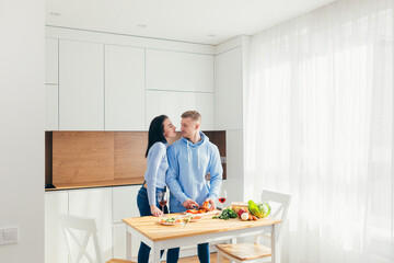 A young couple in love, a man and a woman, are cooking dinner together and having fun in a new apartment