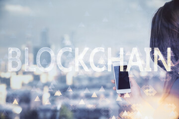 Double exposure of blockchain business sketch hologram and woman holding and using a mobile device.