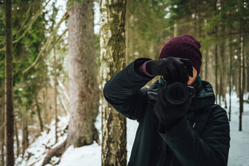 Fototapeta na wymiar Shallow focus of a photographer taking photos against a blurred winter forest background