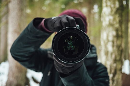 Shallow focus of a photographer taking photos against a blurred winter forest background