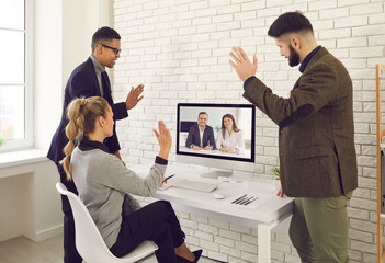 Company workers enjoying virtual business communication and online negotiations. Team of diverse people video calling coworkers or executives for group work meeting and waving hands at computer screen