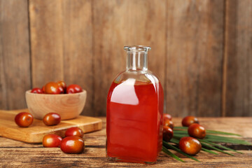 Palm oil in glass bottle, tropical leaf and fruits on wooden table
