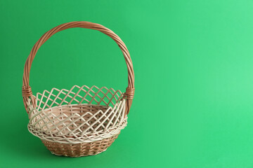 Fototapeta na wymiar Empty wicker basket on green background, space for text. Easter item