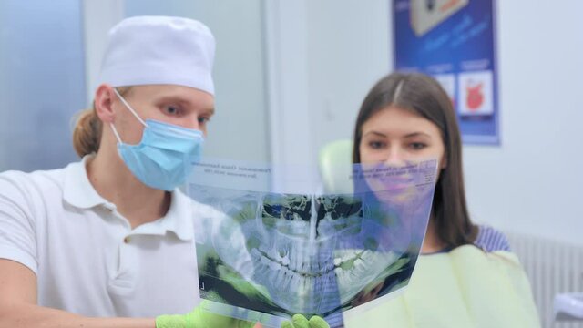 Dentist show panoramic mouth x-ray image to patient
