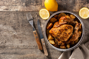 Delivery roasted chicken with potatoes on wooden table.Top view. Copy space