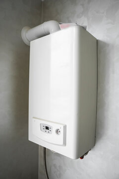 White modern home gas boiler mounted on a grey wall on a kitchen. Water heater. Water heating, ecology.