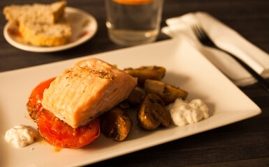 simmered slice of salmon with tomato spinon and coconut sauce on a white plate