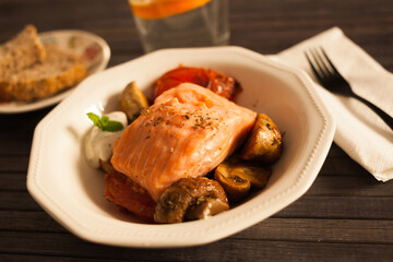 simmered slice of salmon with tomato spinon and coconut sauce in a white bowl