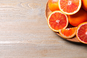 Whole and cut red oranges on wooden table, above view. Space for text
