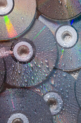Vertical image of shiny and wet CD discs as a background