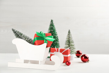 Beautiful Christmas composition with miniature sleigh on white table. Space for text