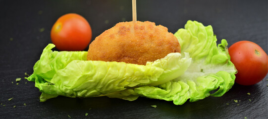 Typical spanish, tapa. Macro, croquettes on small leaves of tudela heart lettuce.