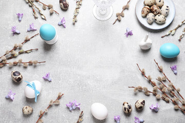 Festive Easter table setting with painted eggs and floral decor on light grey background, flat lay. Space for text