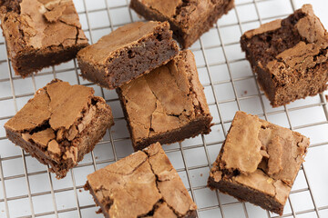Pieces of freshly baked brownies in a square form on a cooling tray. Flat lay composition with...