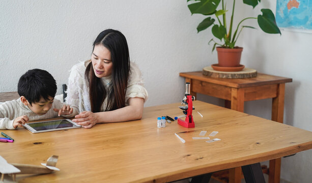 Asian teacher using tablet with little boy at preschool - Focus on kid face