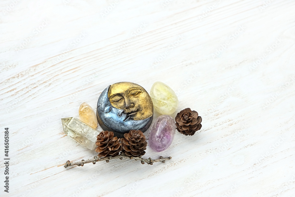 Wall mural symbolic moon wax candle, crystal gemstones and cones on white wooden background. healing minerals f