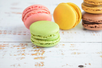Colorful macarons, typical french sweet. White rustic table background.