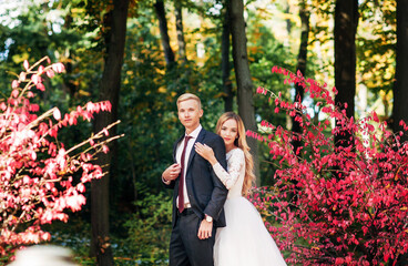 the bride and groom are walking in the autumn park