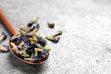Spoon and dry organic blue Anchan on grey table, closeup with space for text. Herbal tea