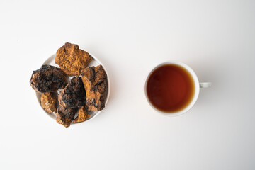 Chaga, birch tree mushroom in white plate and chaga tea on grey background. Natural medicine, antioxidant, superfood.