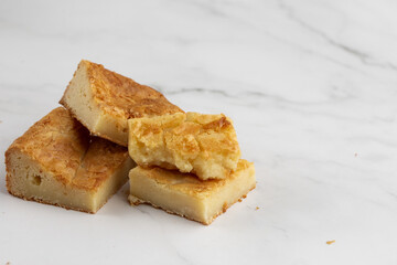 Pieces of freshly baked white chocolate brownies in square form. Flat lay composition with sweet white brownies isolated on white marble background. Delicious blondie brownies. Dessert menu concept. - obrazy, fototapety, plakaty