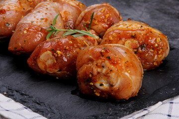 Marinated raw chicken legs on black stone plate. Uncooked marinated chicken
