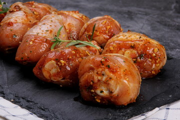 Marinated raw chicken legs on black stone plate. Uncooked marinated chicken