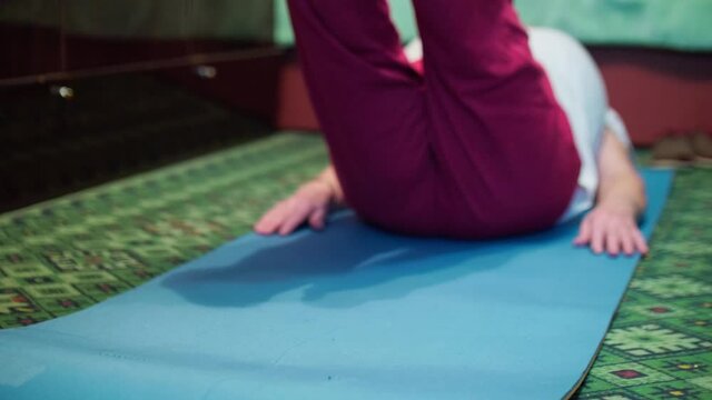 Seniour woman does tibetian gymnastics as morning exercises. Isolation of old people at home during pandemic.