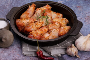 Marinated raw chicken legs on black pan. Uncooked marinated chicken. Marinated chicken drumsticks