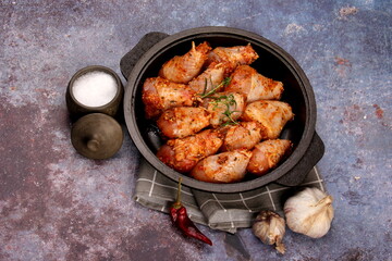 Marinated raw chicken legs on black pan. Uncooked marinated chicken. Marinated chicken drumsticks