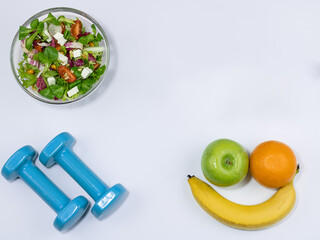 Healthy eating, bowl of fresh mixed salad, dumbble , fresh fruit.