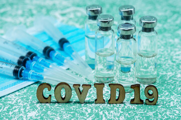Prevention of seasonal diseases. Medical ampoules, syringes, and a mask on a green background. Vaccination against covid-19.