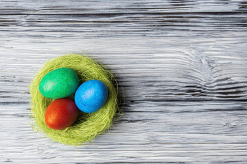 Painted eggs in nest on aged wooden background with copy space