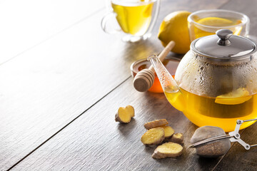 Ginger tea with lemon and honey in crystal glass on wooden table. Copy space
