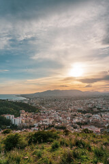 Fototapeta na wymiar Beautiful sunset views of the city of Malaga from a viewpoint on a hill, overlooking the city, the sea, the mountains and the cloudy sky in the background.