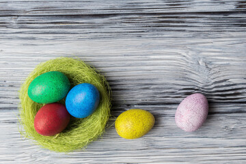 Painted eggs in nest on old wooden background with copy space