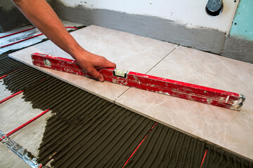Ceramic tiles and tools for tiler. Worker hand installing floor tiles. Home improvement, renovation...