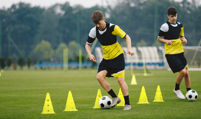 Boys on soccer football training. Young players dribble ball between training cones. Players on...