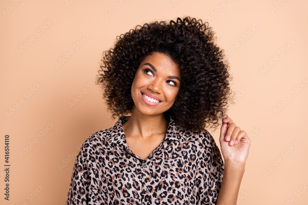 Wall mural Photo portrait of curly woman curious dreaming looking copyspace touching hairdo isolated pastel beige color background