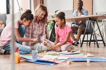 Fototapeta premium Caucasian woman drawing with her multiracial daughters at home