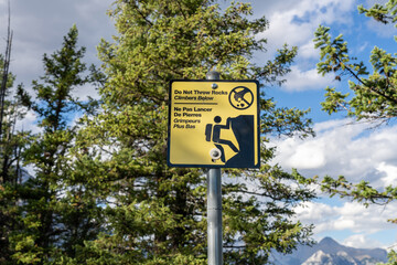 Do not throw rocks climbers below warning sign signpost at Tunnel Mountain Trail. Banff National Park, Canadian Rockies.