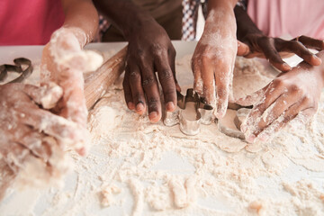 Family squeeze out the dough using cookie cutters in kitchen at home